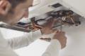 Professional plumber maintaing a central heating system boiler