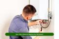 Homeowner checking boiler system and reading about UK grants to replace old heating with a new energy-efficient boiler