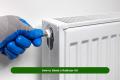 Person using a radiator key to bleed a radiator in a UK home